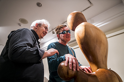 Una persona ciega, acompañada por un voluntario, toca una de las esculturas de la exposición Hilemórfica del Museo Tiflológico