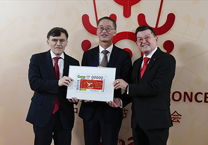 Alberto Durán, vicepresidente de la ONCE, Yao Jing, embajador de China en España, y Ángel Sánchez, director general de la ONCE, sostienen una lámina enmarcada con el cupón