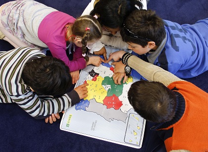 Varios niños en clase, en torno a un mapa de España accesible